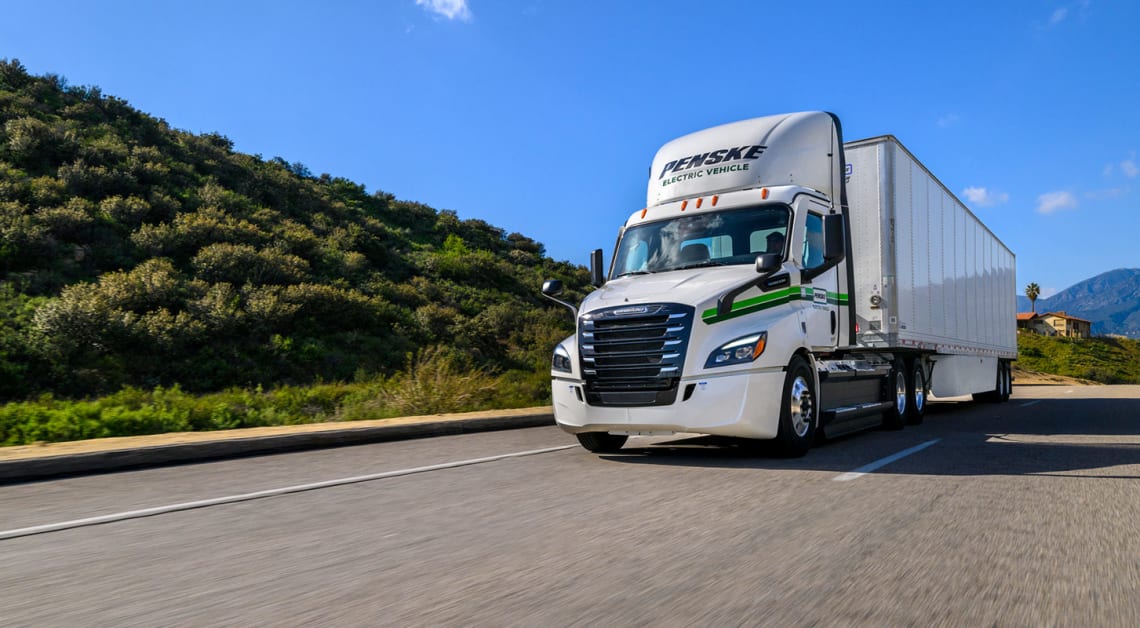 Image of a Penske electric semi truck driving down the road.